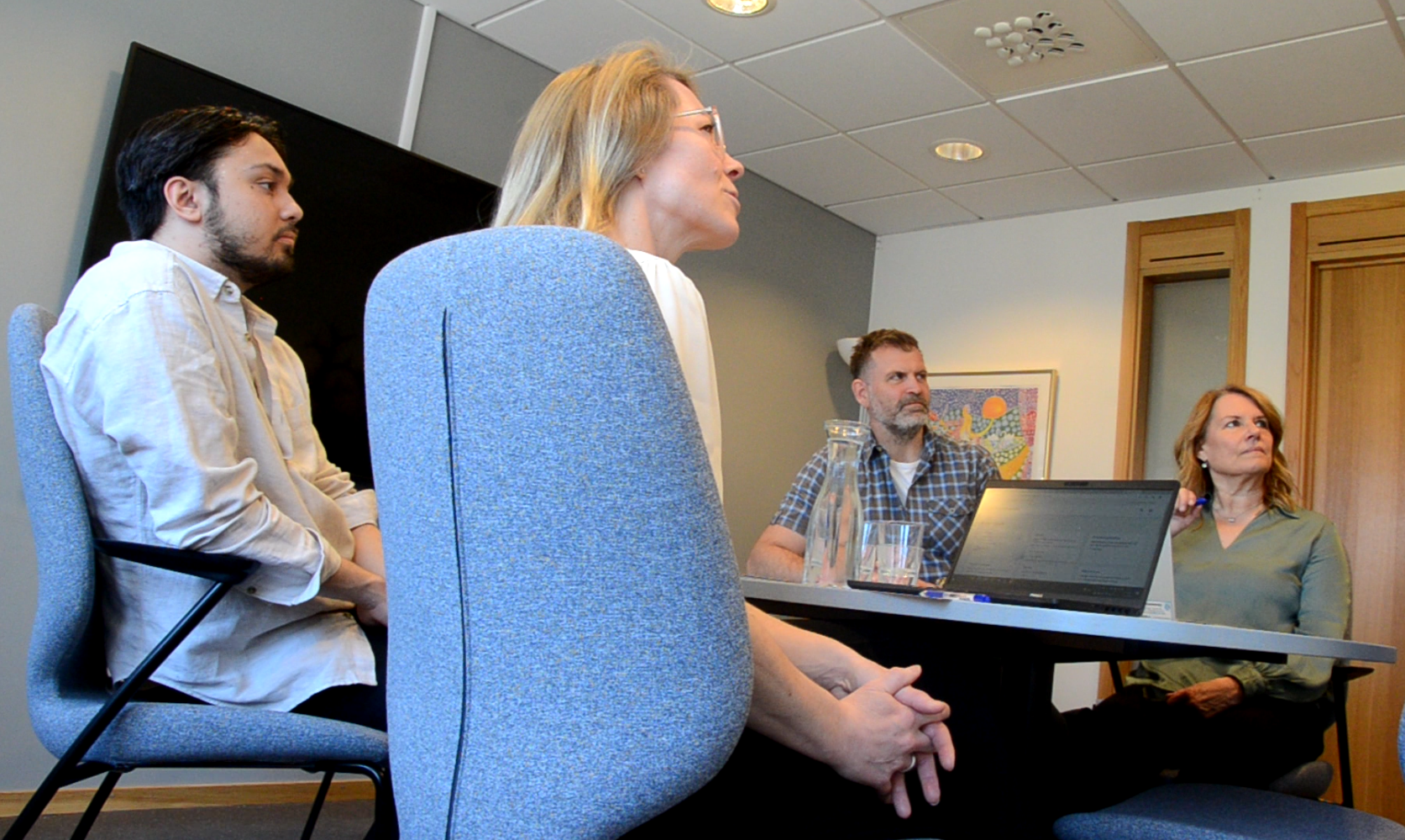 Fyra personer sitter i möte runt ett bord, vinkel snett underifrån